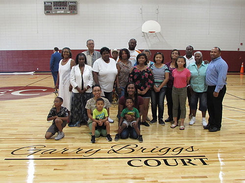 Members of Garry Briggs family stand behind an emblazoned branding of Briggs’s name on the gym floor. Photo: Andrea Wright/Urban News.