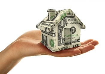 hand holding house made of money