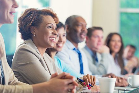 African American businesswoman listening to seminar speaker at business conference
