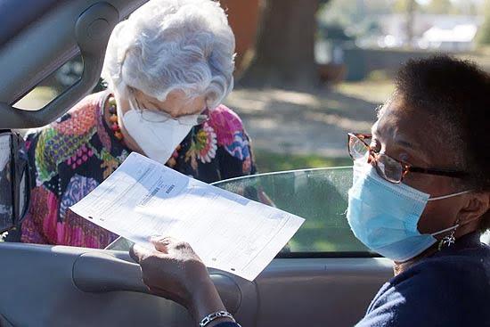Belinda Dancy hands Chief Judge Margaret Hendricks her curbside ballot Tuesday at the Braswell Center in Tarboro, NC.