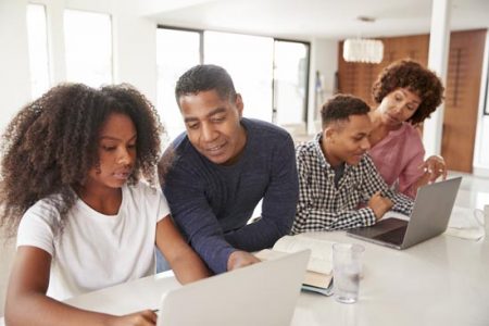 Middle aged black parents helping their teenage kids using laptops to do homework, close up
