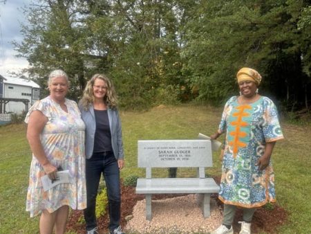 Terri Wells, Vicki Jennings, and Phyllis Utley stand next to the Sarah Gudger memorial bench in Swannanoa.